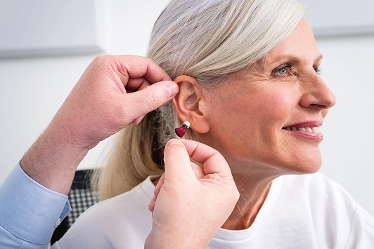 Seniorin erhält Hörgerät vom Akustiker, Hörakustik und Hörhilfe für besseres Hören.